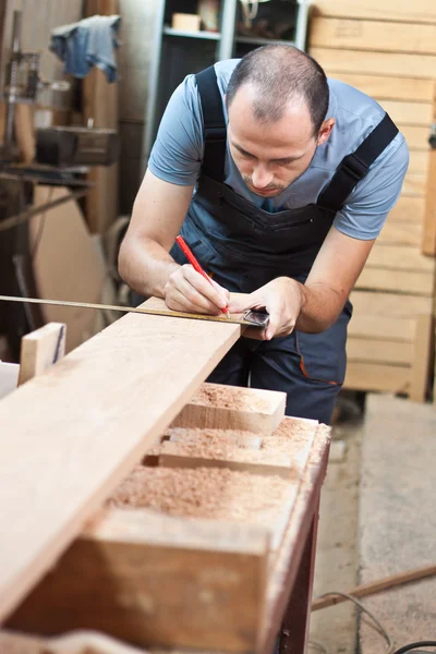 Человек измеряет деревянную доску — стоковое фото
