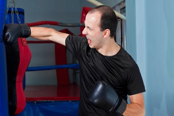 Boxeador golpeando agresivamente una bolsa de arena —  Fotos de Stock