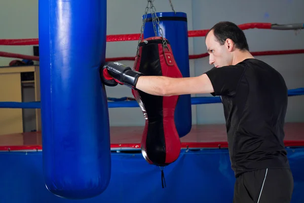 Boxeador perforando una bolsa de arena con la mano trasera — Foto de Stock
