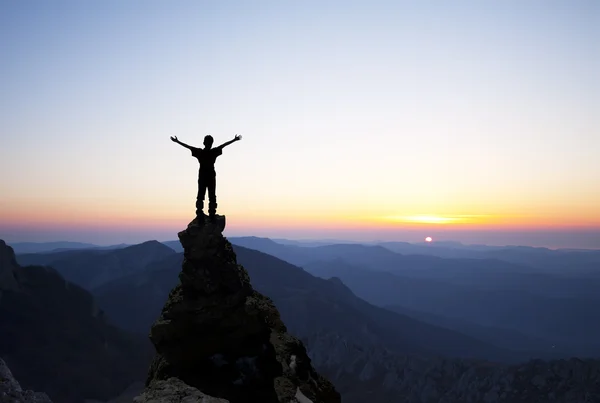 El hombre en la cima de la montaña busca el sol — Foto de Stock