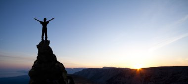 Man on top of the mountain reaches for the sun clipart