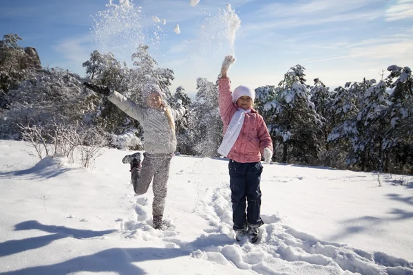 Twee meisjes spelen op sneeuw — Stockfoto