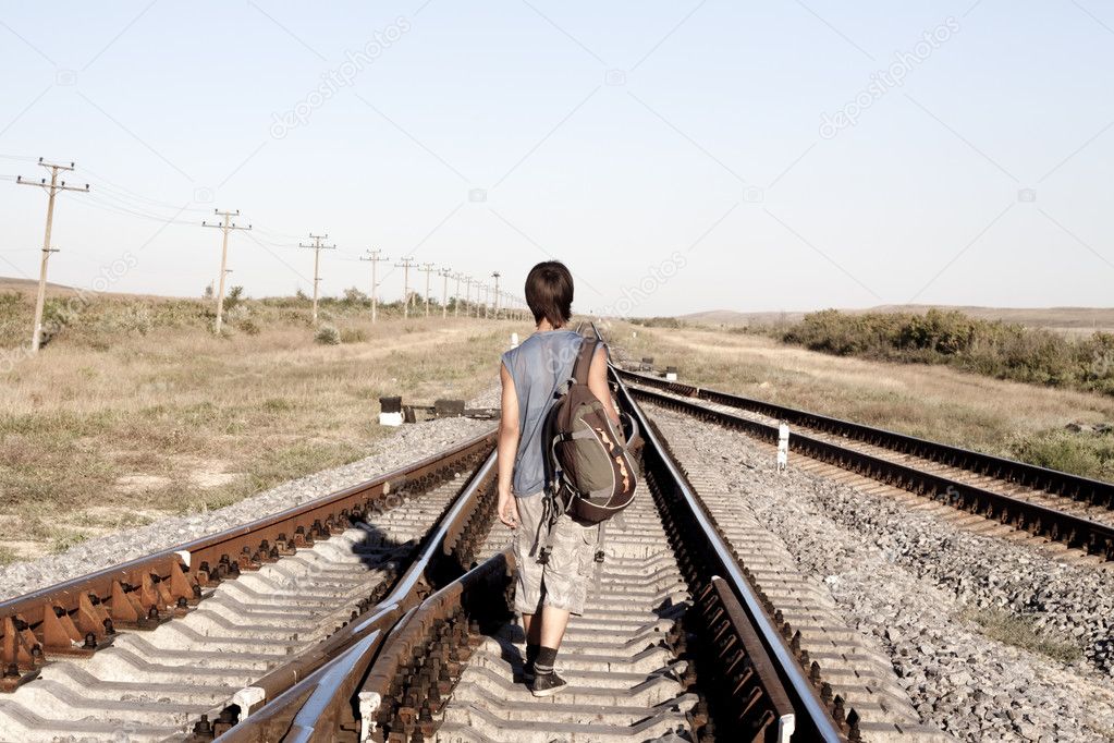 Teen boy walking on rail road