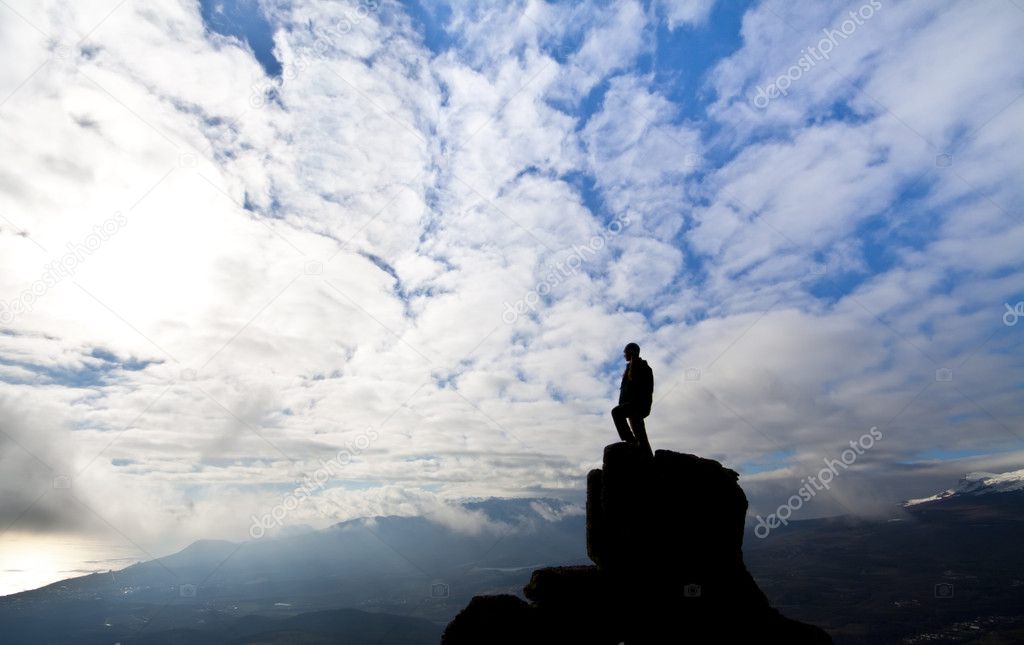 Woman on top of the mountain reaches for the sun