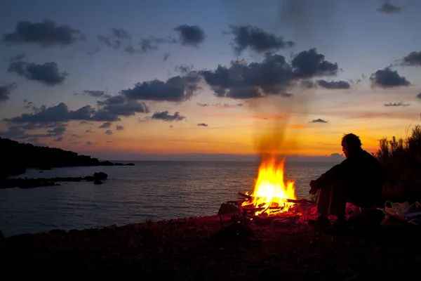 Muž sedí u ohně — Stock fotografie