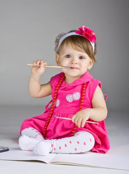 Seated little girl holding a paintbrush — Stock Photo, Image