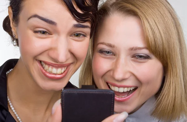 Две смеющиеся женщины вблизи смотрят на мобильный телефон — стоковое фото