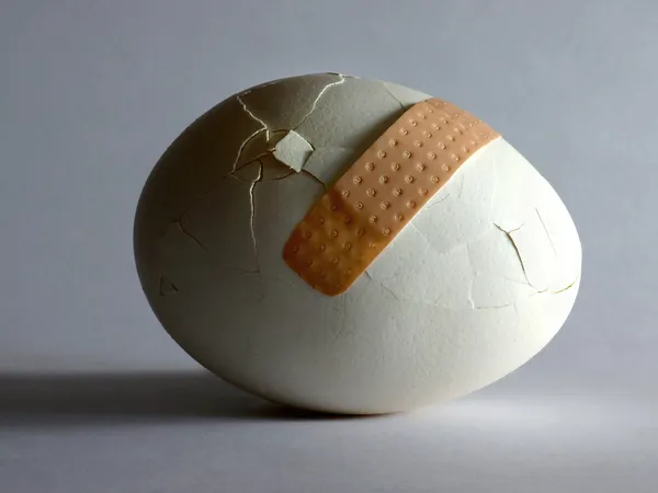 Broken egg with sticking plaster — Stock Photo, Image