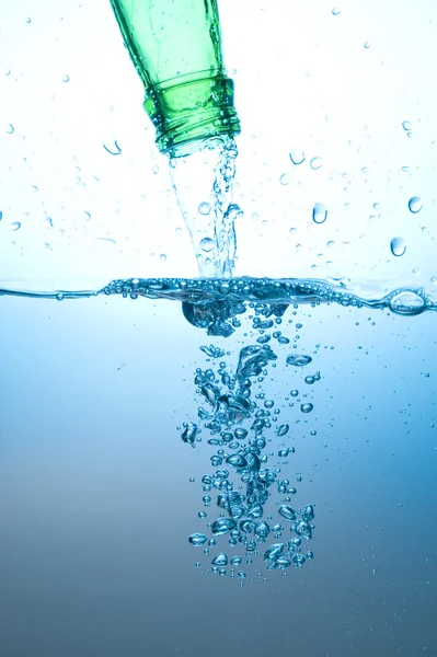 Grüne Flasche und spritzendes Wasser — Stockfoto