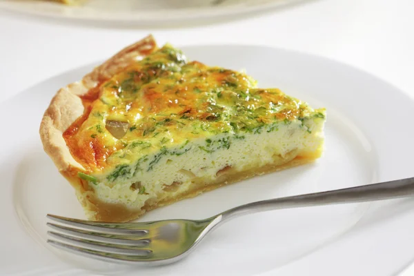 A slice of homemade quiche on a white plate with a fork — Stock Photo, Image