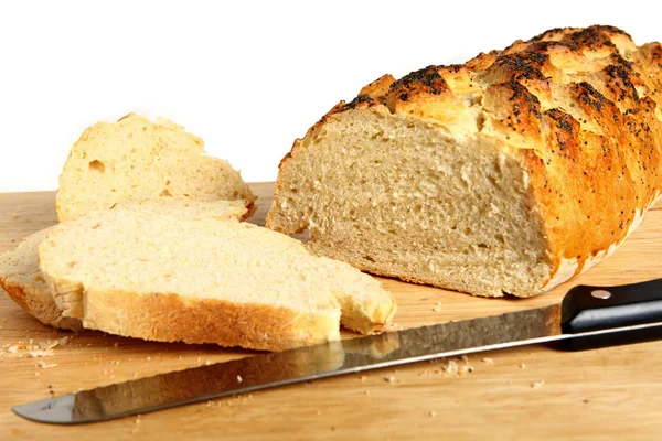Um pão caseiro numa tábua de pão com uma faca de pão — Fotografia de Stock