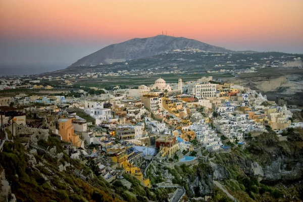 Una vista sobre la ciudad principal de Fira en la isla de Santorini al atardecer . —  Fotos de Stock