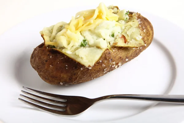 Baked potato with fork on plate — Stock Photo, Image
