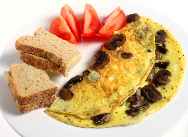 A mushroom omelet served with brown bread and butter and sliced tomato — Stock Photo, Image