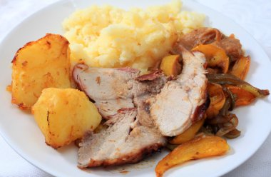 A meal of roast pork, served with roast potatoes and oven-roasted peppers clipart