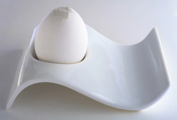 Белое яйцо в стакане с треснувшим верхом — стоковое фото