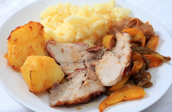 A meal of roast pork, served with roast potatoes and oven-roasted peppers — Stock Photo, Image
