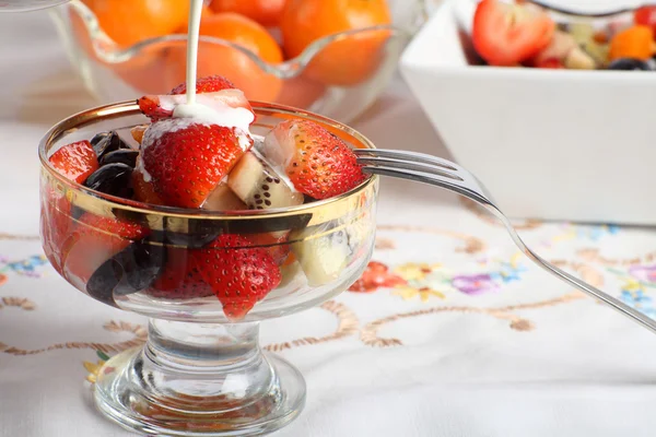Krem być wylana na sałatki ze świeżych owoców w misce szkła — Zdjęcie stockowe