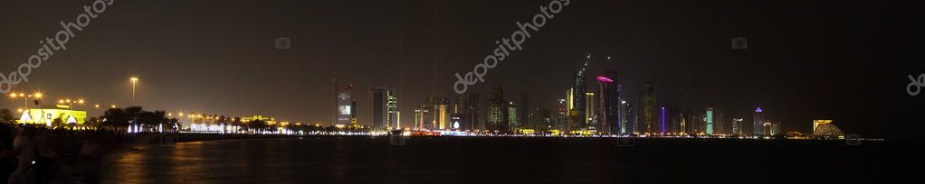 A view of the the skyline of Doha lit up for National Day, 2009, just ahead of the firework display, logos removed. Part of the crowd can be seen on the left, b