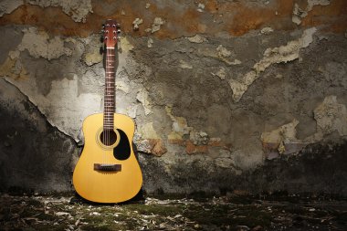 Acoustic guitar against grungy wall clipart