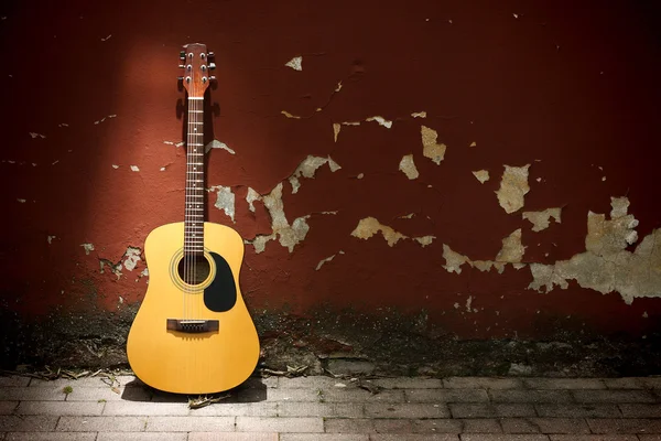 Акустическая гитара против громоздкой стены — стоковое фото