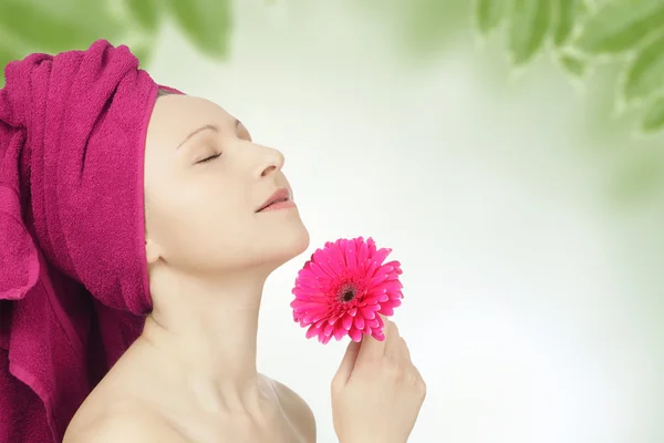 Giovane donna con asciugamano e fiore di gerbera — Foto Stock