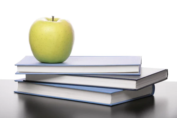 Три книги и яблоко на столе — стоковое фото