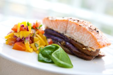 Baked salmon on bed of grill aubergine with serving of salsa clipart