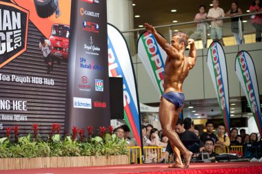 TOA PAYOH, SINGAPORE - MARCH 12. Participant for bodybuilding competion flexing a pose at Toa Payoh Hub, 12 March 2011, Singapore. clipart
