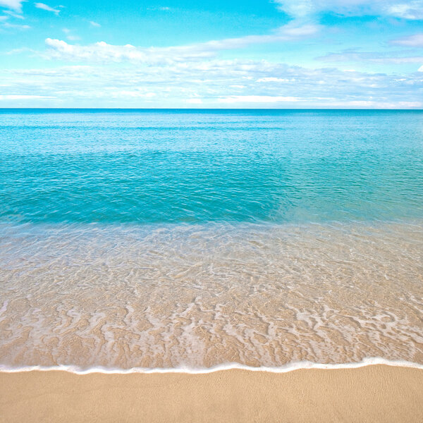 Beautiful sandy beach with calm water against blue skies.