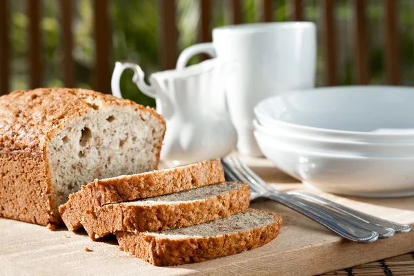 Meal setting with sliced banana bread and serving bowls. — Stock Photo, Image