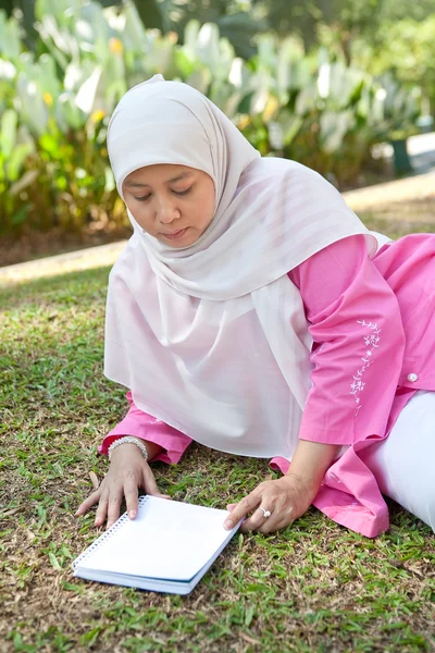 Mulher muçulmana madura bonita desfrutando do parque com um livro — Fotografia de Stock