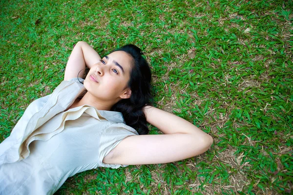 Young female laying on the grass, thinking — Stock Photo, Image