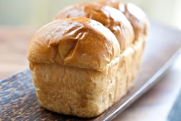 Delicious sweet brioche on wooden plate — Stock Photo, Image