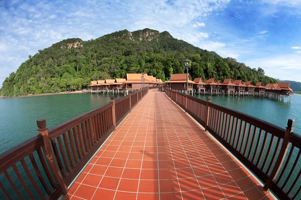 Loopbrug boven water met uitzicht op traditionele resort chalet op een tropisch eiland — Stockfoto