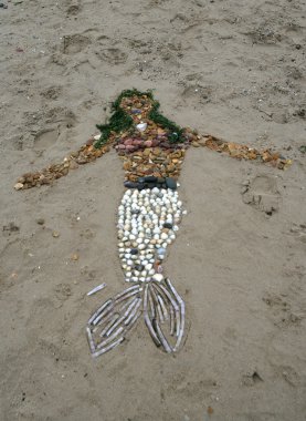 Mermaid built on beach with stones and shells clipart