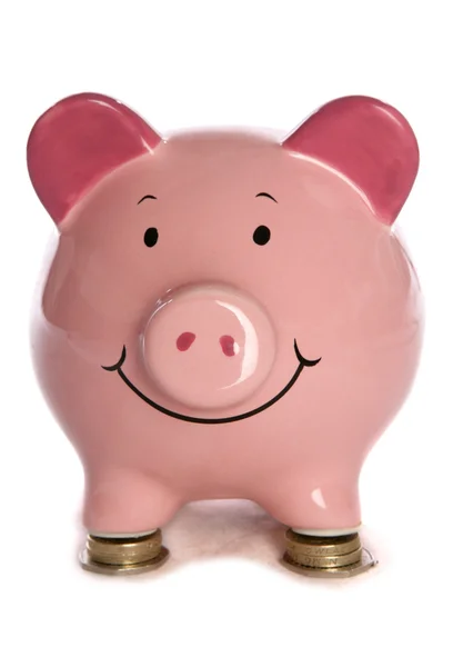 Piggybank descansando en monedas de libras — Foto de Stock