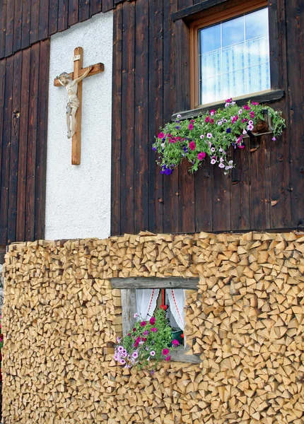 Ledge of a window surrounded by flowers freshly cut wood and wooden crucifi — Stock Photo, Image
