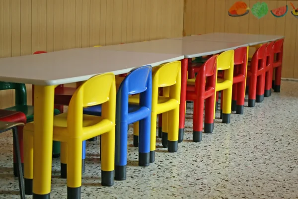 Rangée colorée de chaises vides dans une salle à manger d'une maternelle — Photo