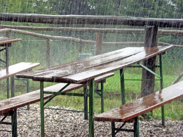 Duş sırasında terk edilmiş bir bayram için piknik masaları — Stok fotoğraf
