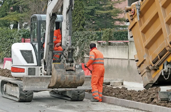 Los trabajadores con el mono y una excavadora para trabajar en una construcción de carreteras si — Foto de Stock