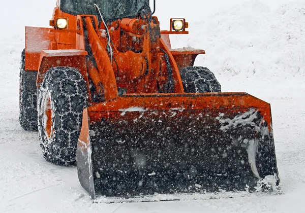 Le chasse-neige orange nettoie les rues lors d'une tempête de neige — Photo