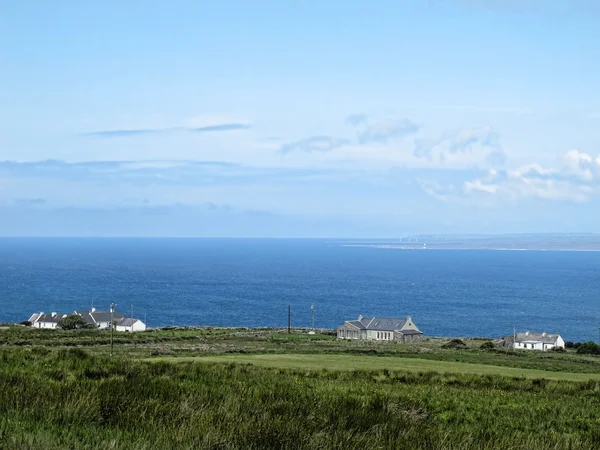 Niebieskie Morze Irlandzkie z domów na klifie morza i łąka — Zdjęcie stockowe