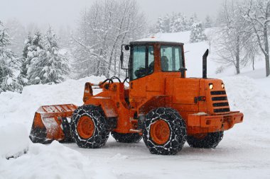 Orange snow plows to work clearing the snow from the road clipart