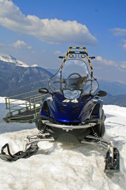 Snowmobile parked in the mountain on snowy slopes clipart