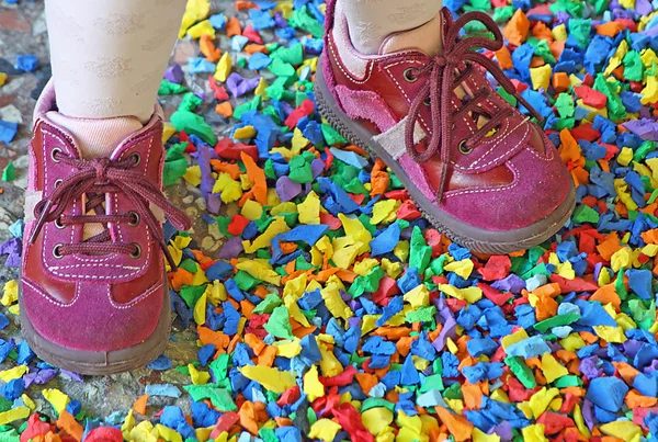 stock image Small purple shoes of a little girl in the midst of a colorful confetti car