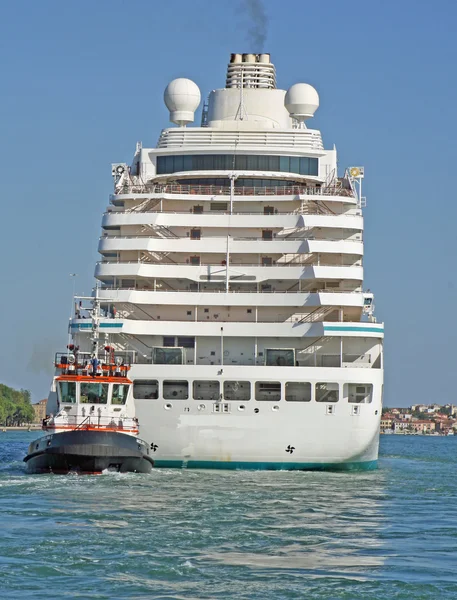 Huge cruise ship sets sail from the port of Venice accompanied by a small t — Stock Photo, Image