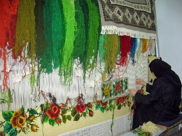Mulher que trabalha a lã colorida e ela produz tapetes — Fotografia de Stock