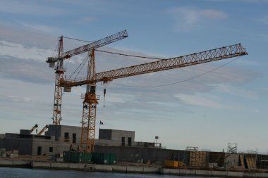 Two large cranes during the construction of a dam clipart