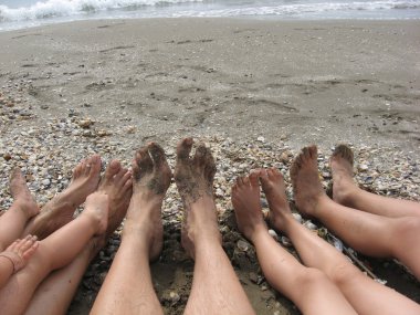 Feet of a family on the beach by the ocean clipart